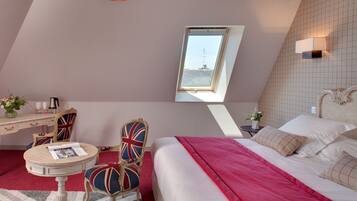A bedroom with a bed, a desk, and a chair. There is a window with a view of the outside.