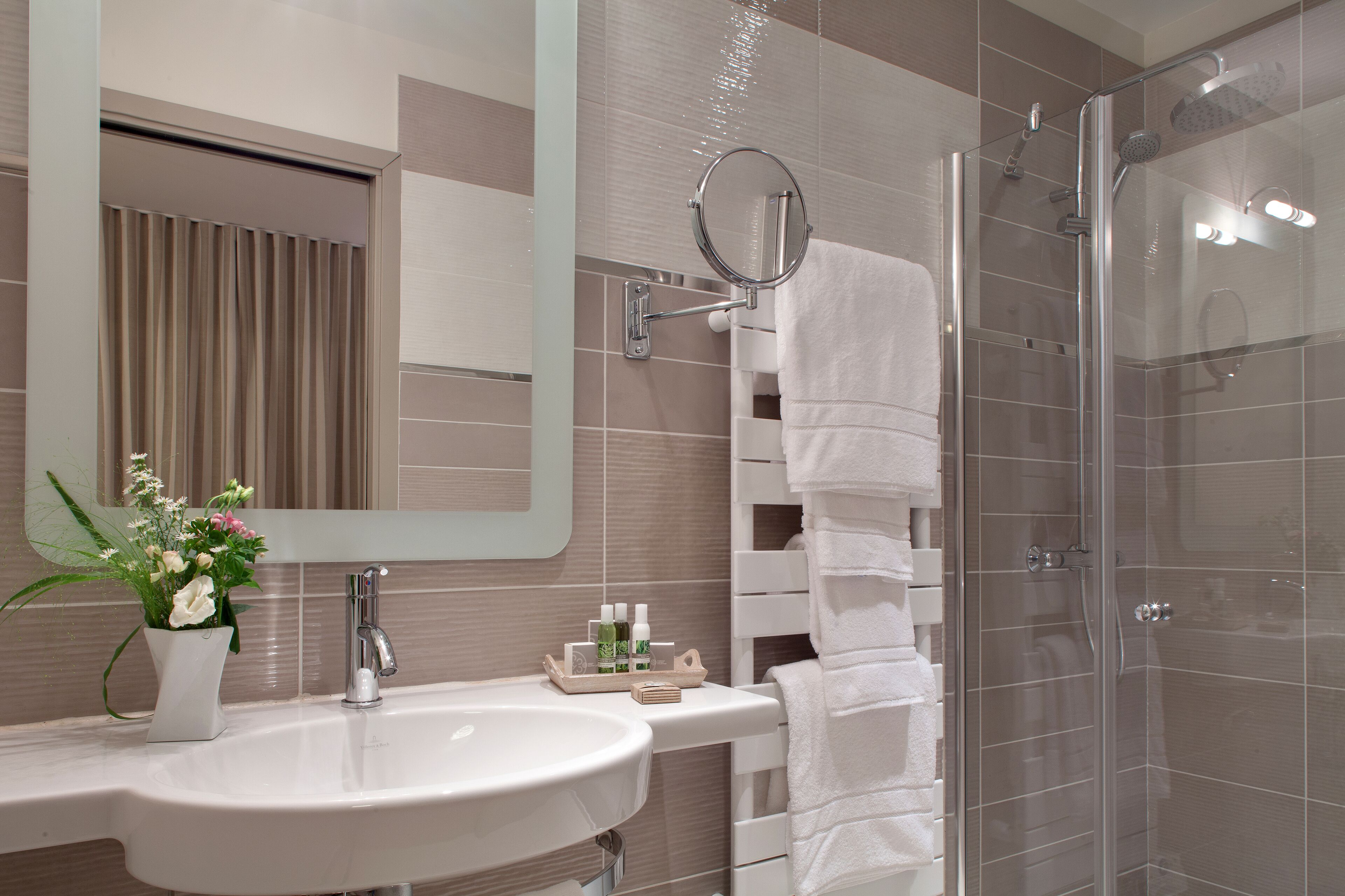 A modern bathroom with a sink, mirror, and shower.
