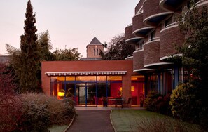 A modern building with a glass facade, a brick exterior, and a small tower.