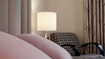 A hotel room with a bed, a chair, a lamp, and curtains.