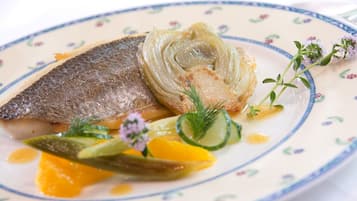 A plate with fish, vegetables, and a floral pattern on the plate.