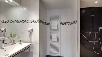 Casa de banho moderna com uma sanita branca, secador de cabelo e área de duche.
