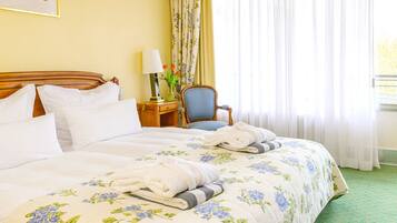 Habitación de hotel con una cama grande, una silla, una mesita de noche y una ventana con cortinas.