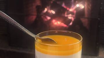 A dessert in a glass with a spoon, set against a background of a fireplace.