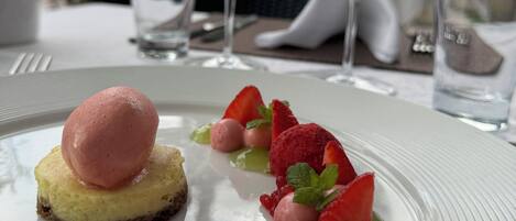 A dessert plate with a scoop of ice cream, strawberries, and mint leaves.