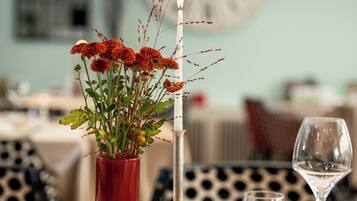 Una mesa de comedor dispuesta con platos, cubiertos, un florero con flores y una vela.