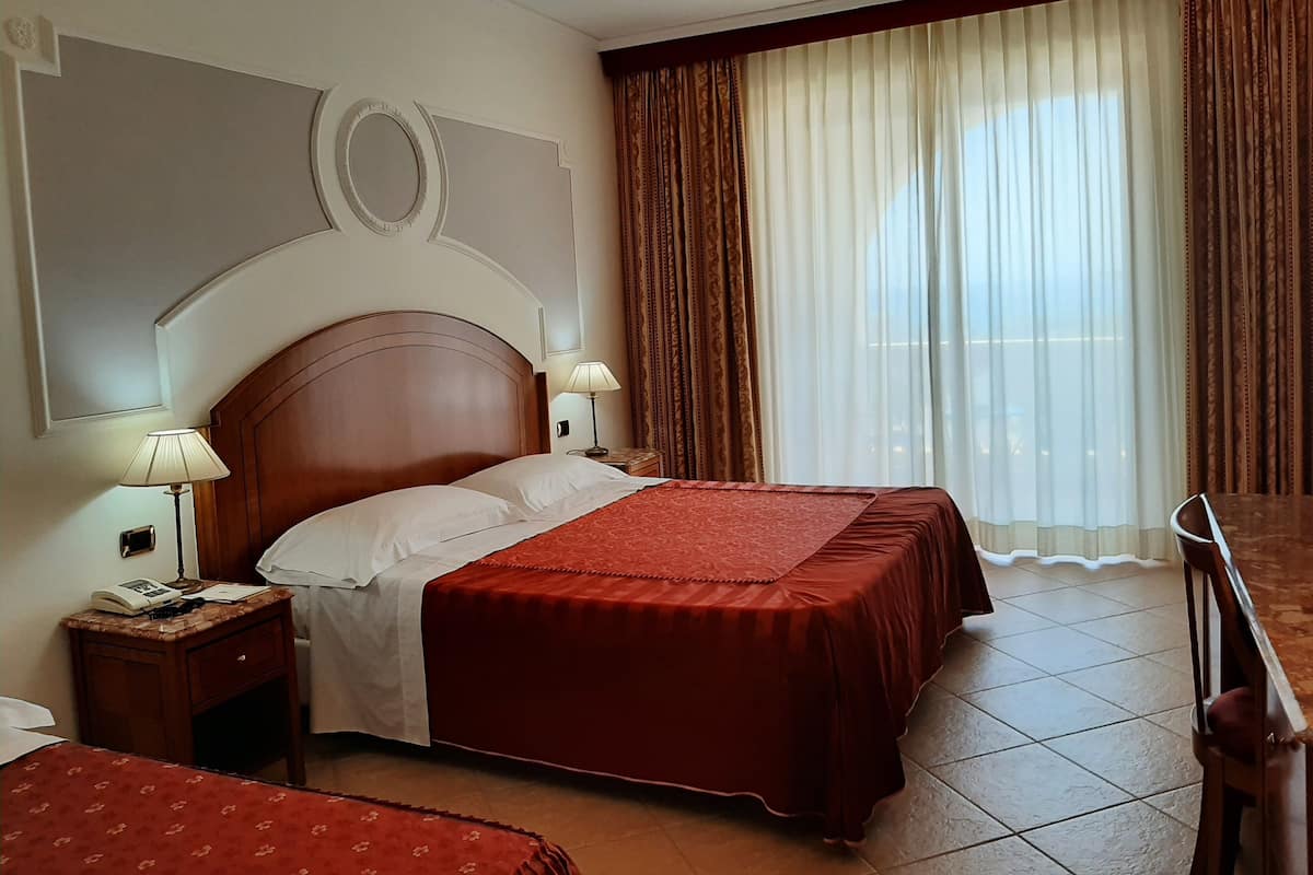 Ein Hotelzimmer mit einem großen Bett, zwei Nachttischen, einem Schreibtisch und einem Sessel.