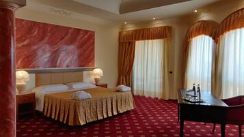 Une chambre d’hôtel avec un grand lit, un bureau avec une chaise et une vue sur l’extérieur à travers les rideaux.