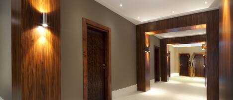 A modern hallway with wooden paneling, recessed lighting, and a tiled floor.