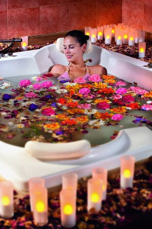 A bathtub filled with colorful flowers and surrounded by candles. - Ikbal Thermal Hotel & Spa (Afyonkarahisar)