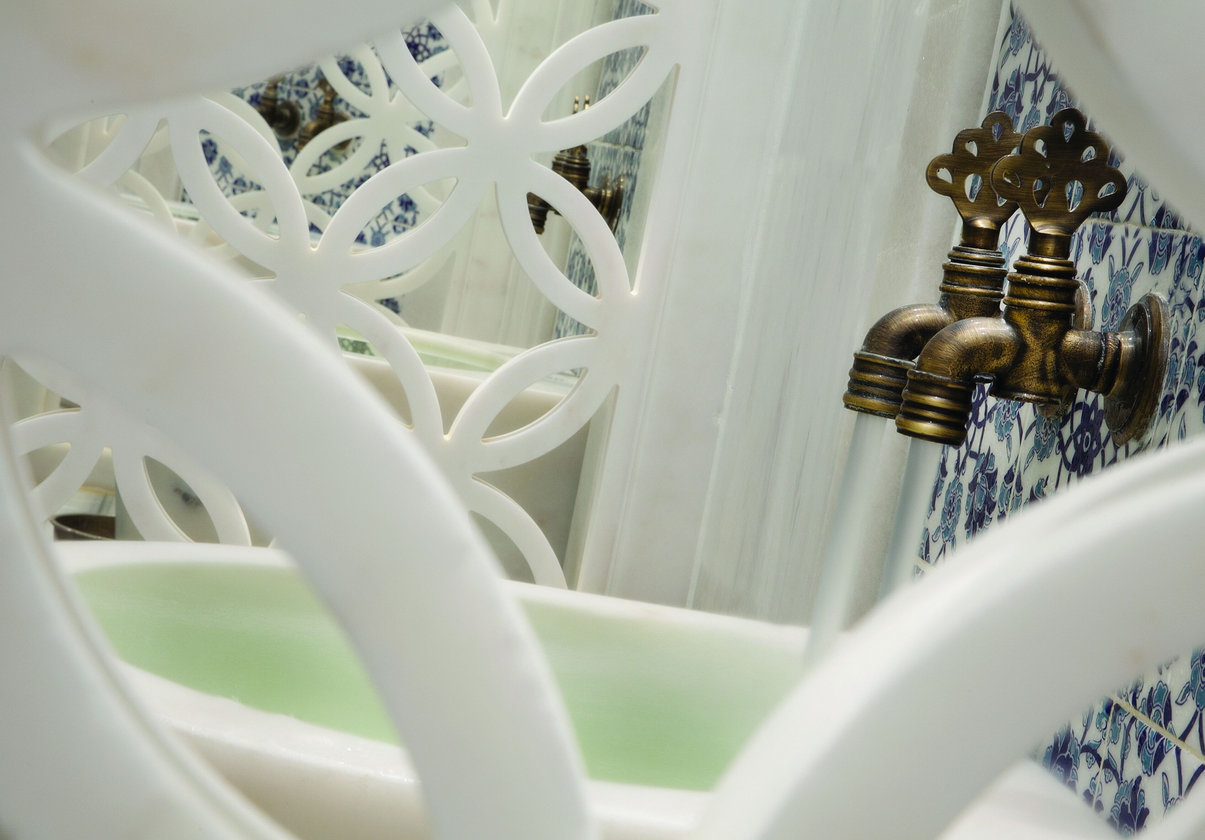 Une salle de bain avec une baignoire blanche, un robinet en laiton et des carreaux aux motifs bleus et blancs.