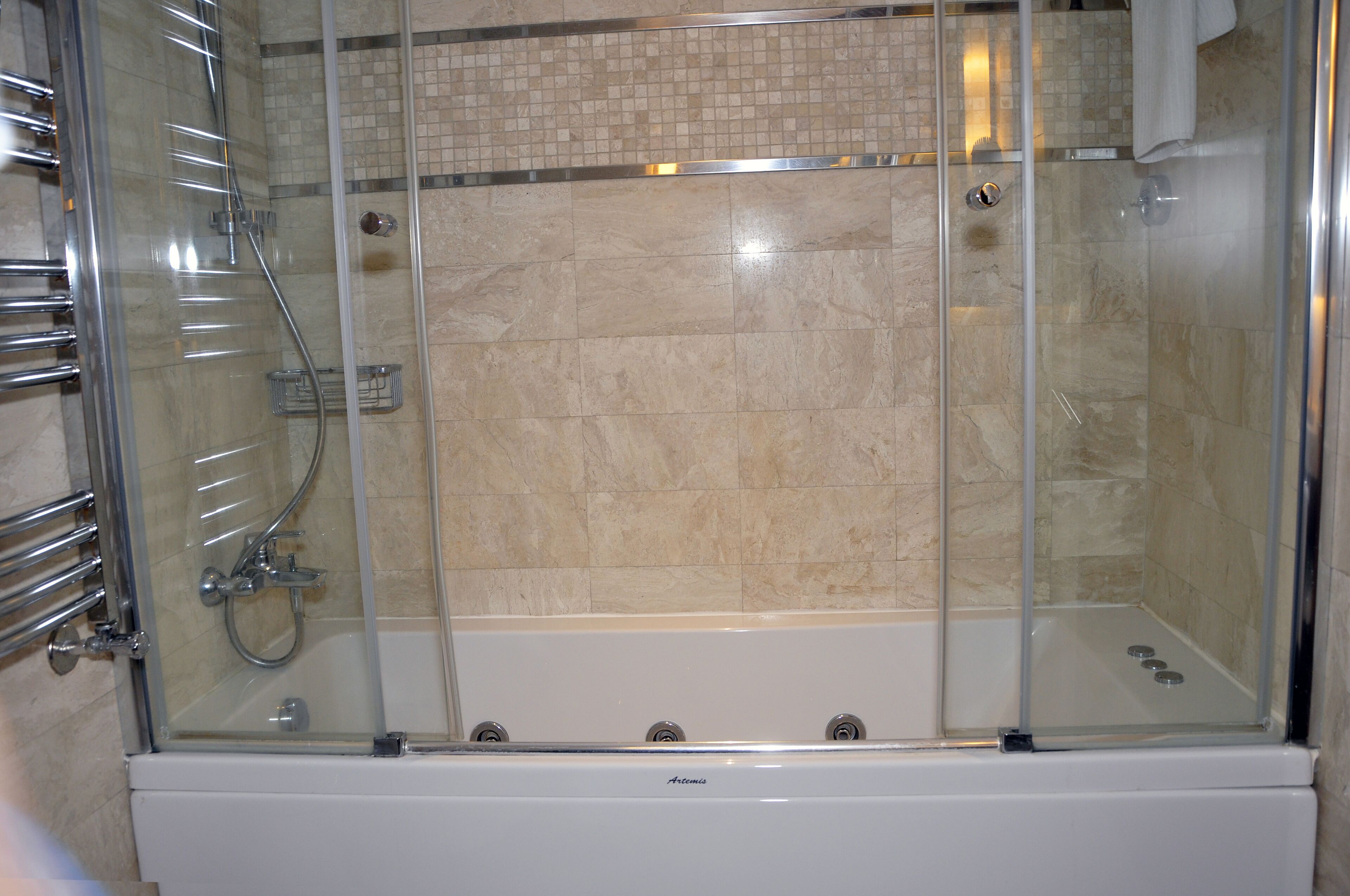 A glass-enclosed walk-in shower with a tiled wall and a chrome showerhead.