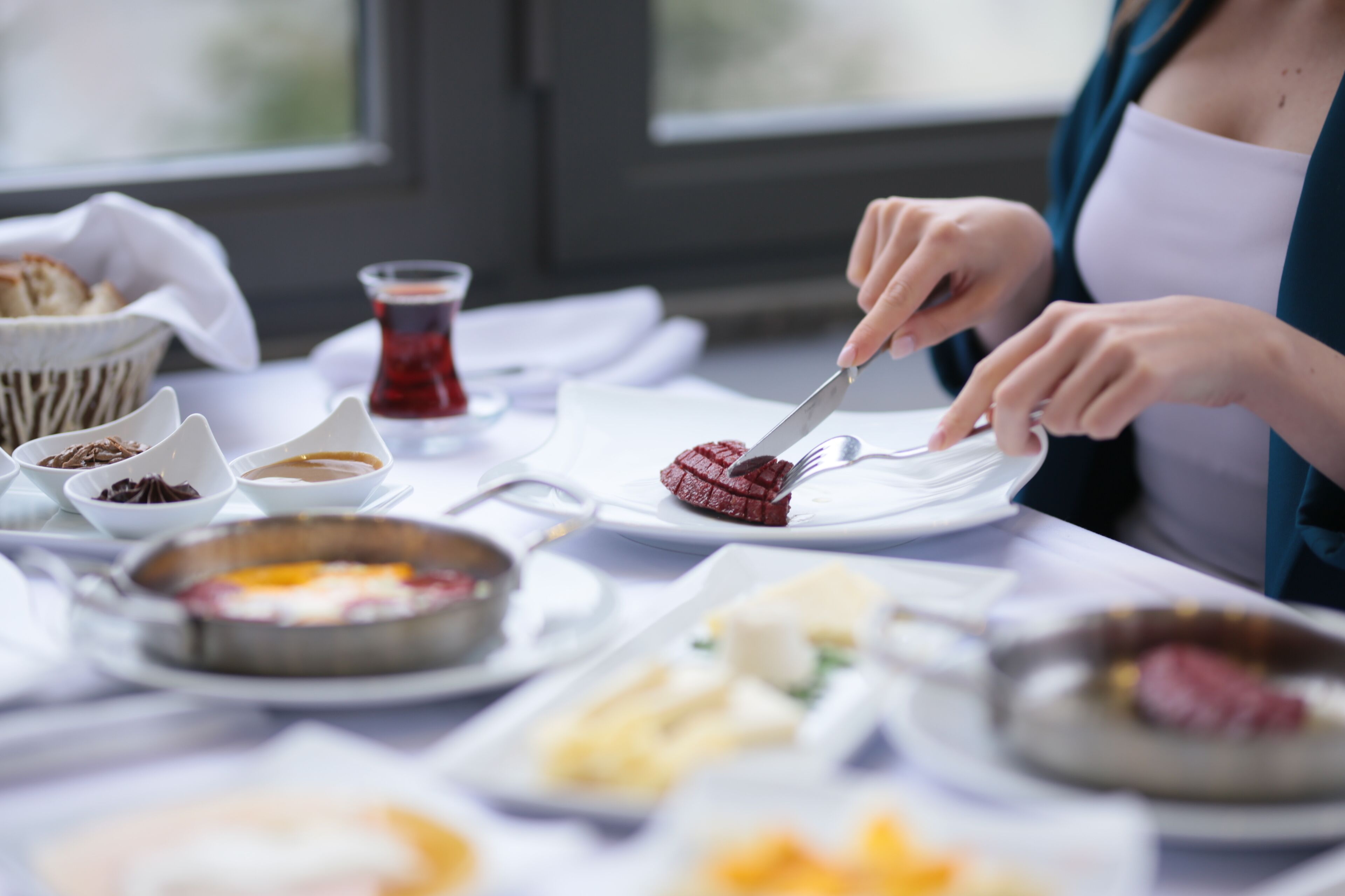 A dining table with various dishes, including a plate with red meat and a bowl of soup.