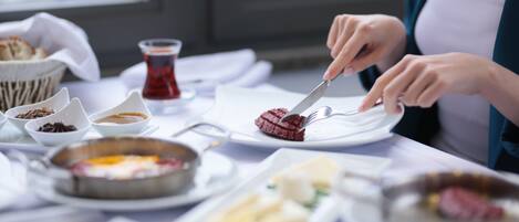 A dining table with various dishes, including a plate with red meat and a bowl of soup.