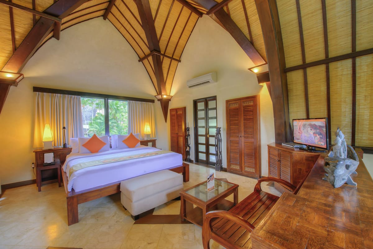Une chambre spacieuse avec un grand lit, des meubles en bois et un téléviseur.