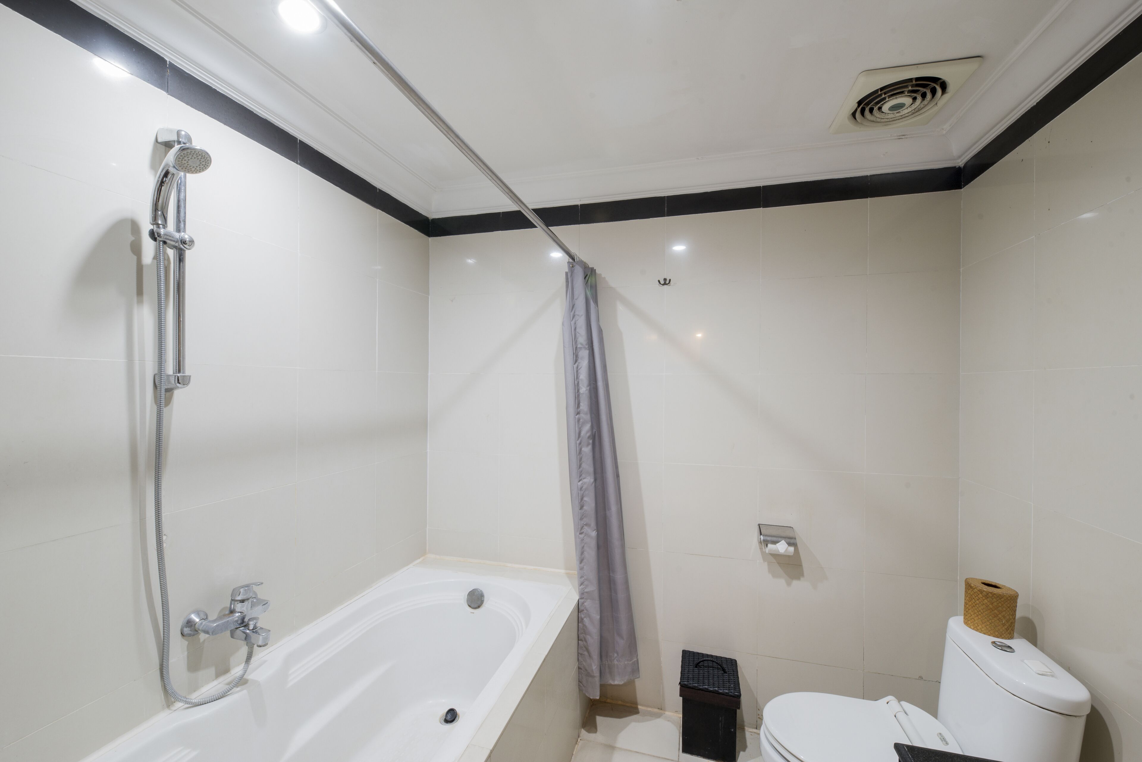 Een badkamer met een badkuip, douche, toilet en een prullenbak.