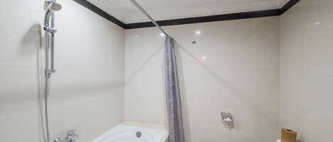 Une salle de bain équipée d’une baignoire, d’une douche, de toilettes et d’une poubelle.