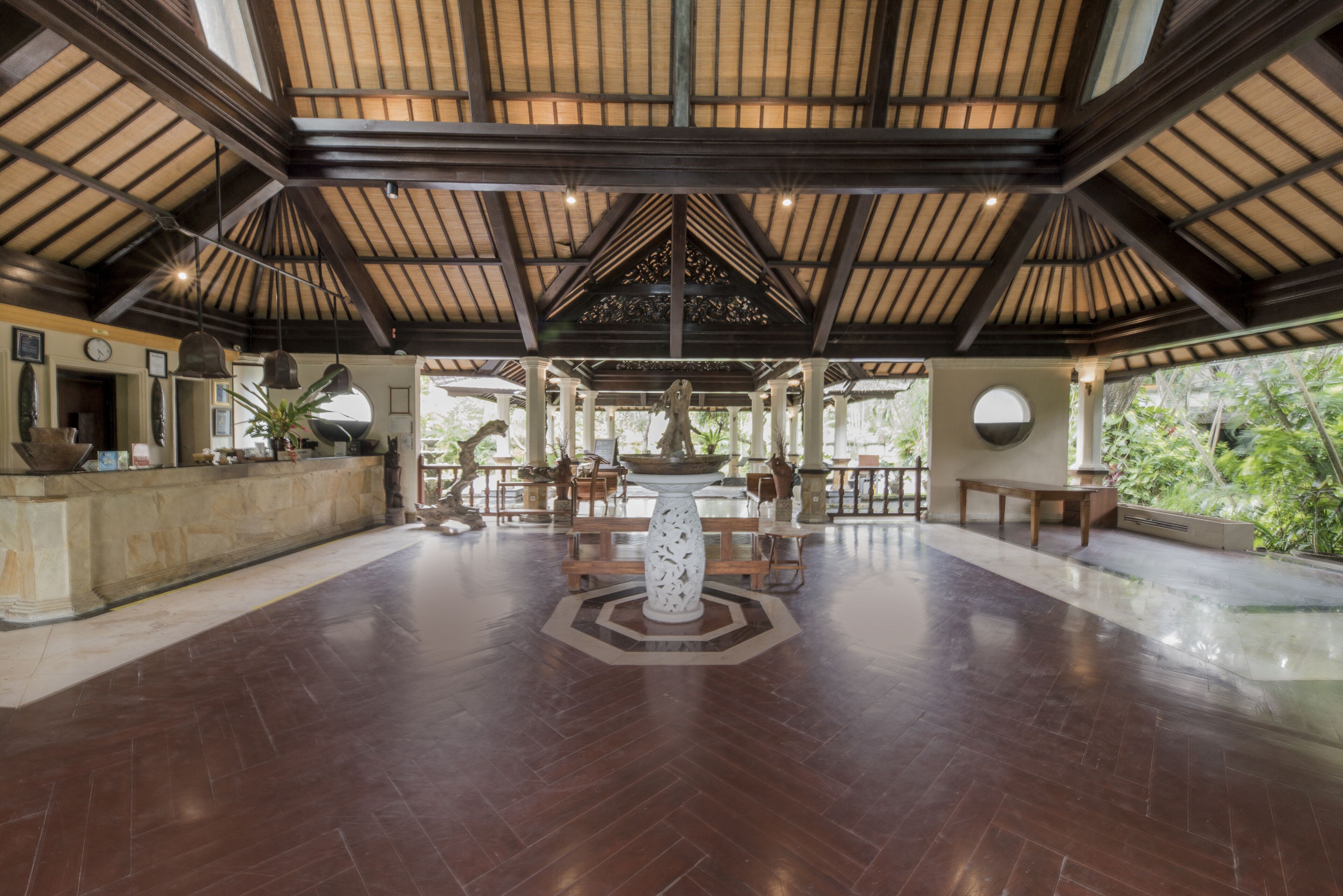 A spacious lobby with a high ceiling, a central decorative fountain, and a seating area with tables and chairs.