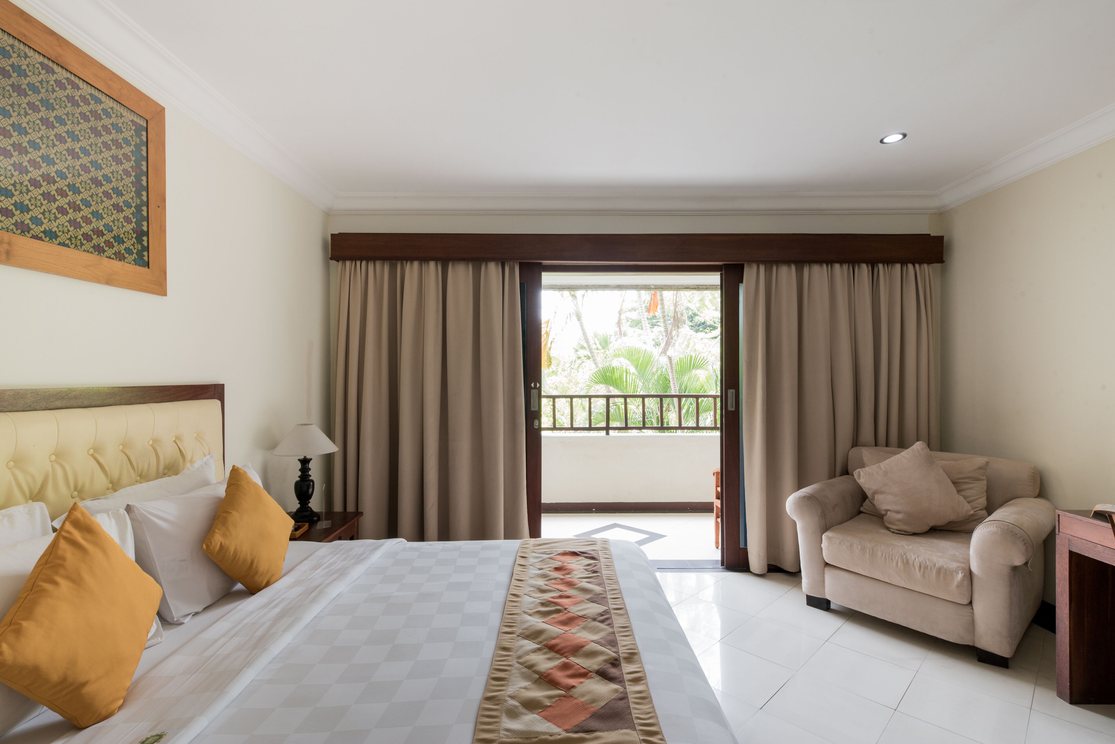 A hotel room with a bed, a sofa, a balcony, and curtains.