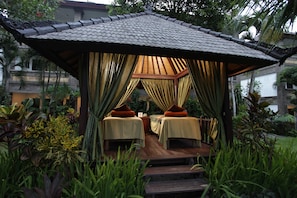 A gazebo with two beds, surrounded by lush greenery and a tiled roof. - Hotel Vila Lumbung (Seminyak)