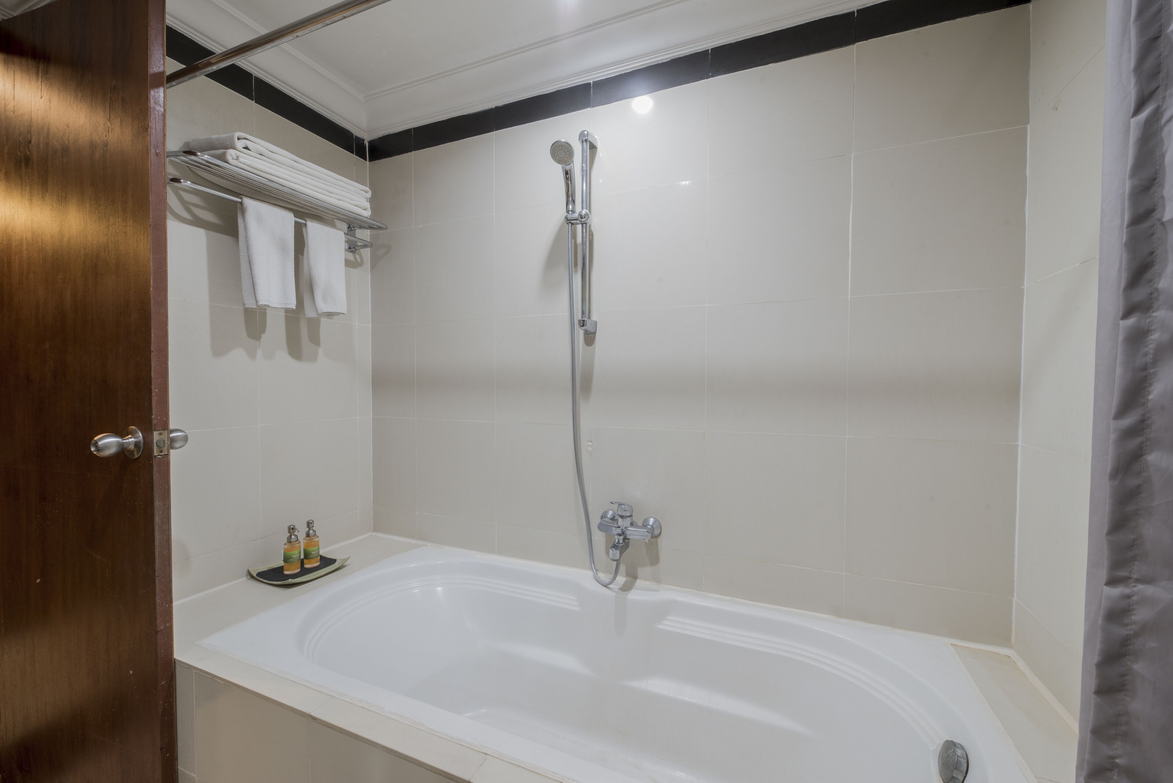 A modern bathroom with a freestanding bathtub, a showerhead, and neatly folded towels on a rack.