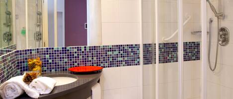 A modern bathroom with a glass-enclosed shower, a vanity with a mirror, and a tiled backsplash.
