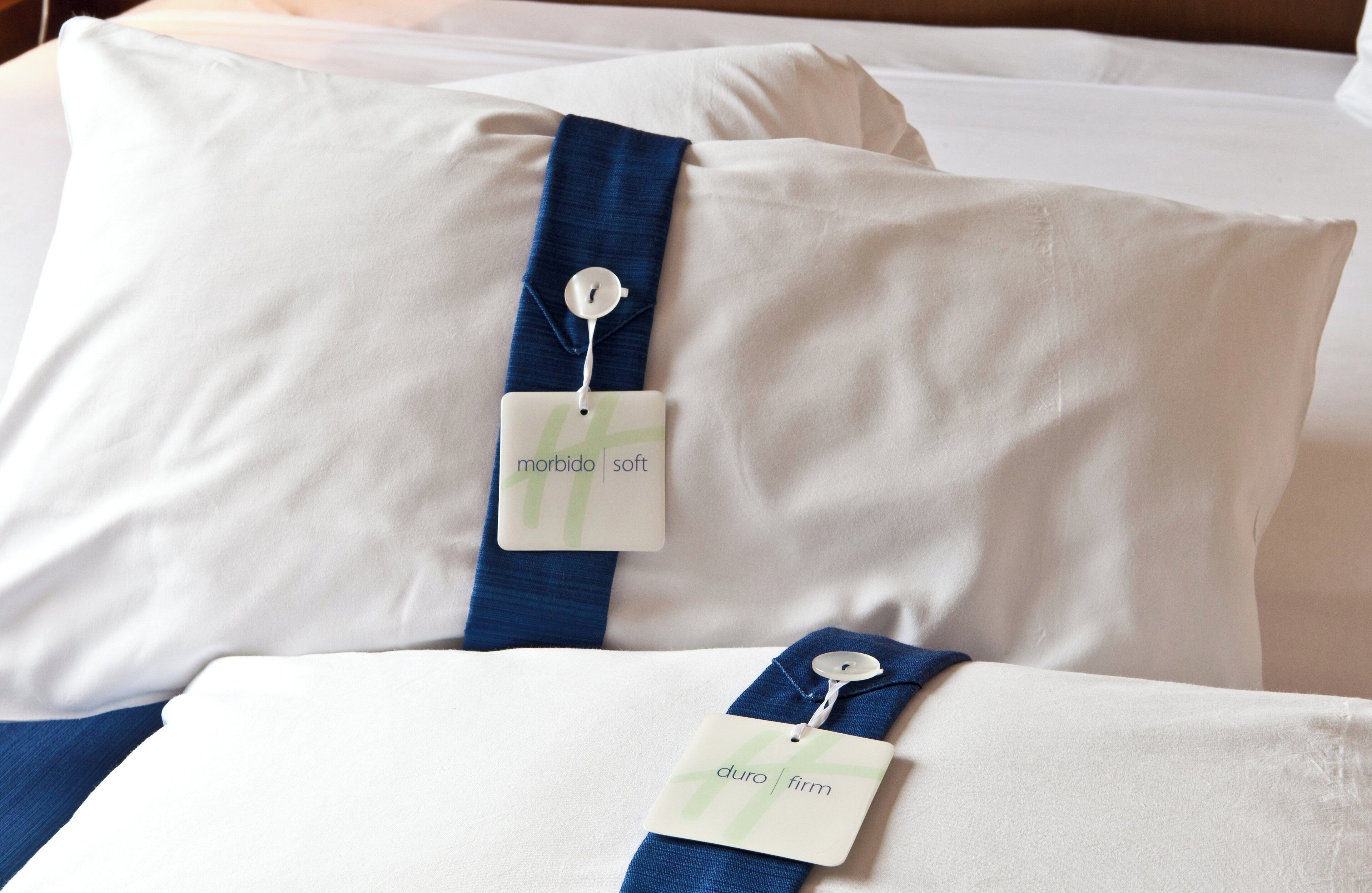 Two pillows with tags on a bed.