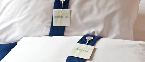 Two pillows with tags on a bed.