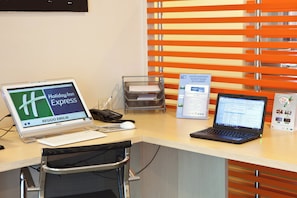 Een bureau met een computer, telefoon en laptop.