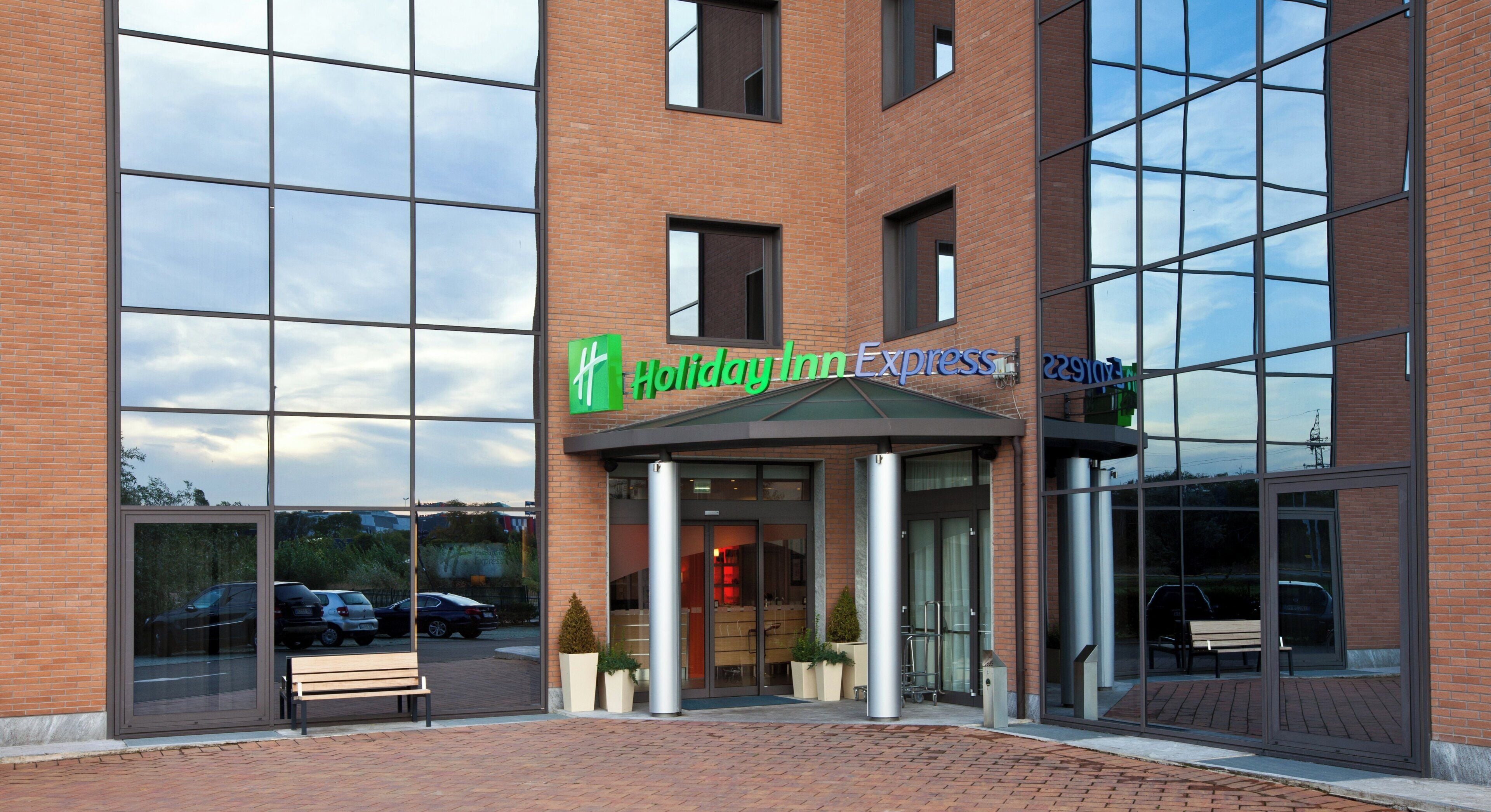 Edificio Holiday Inn Express con fachada de ladrillo, ventanas grandes y un toldo verde.