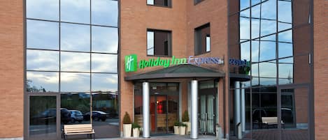 A Holiday Inn Express building with a brick facade, large windows, and a green awning.