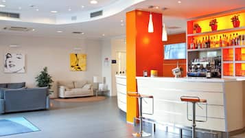 Un hall d’hôtel comprenant un comptoir d’accueil, un bar, des espaces pour s’asseoir et des œuvres d’art accrochées aux murs.