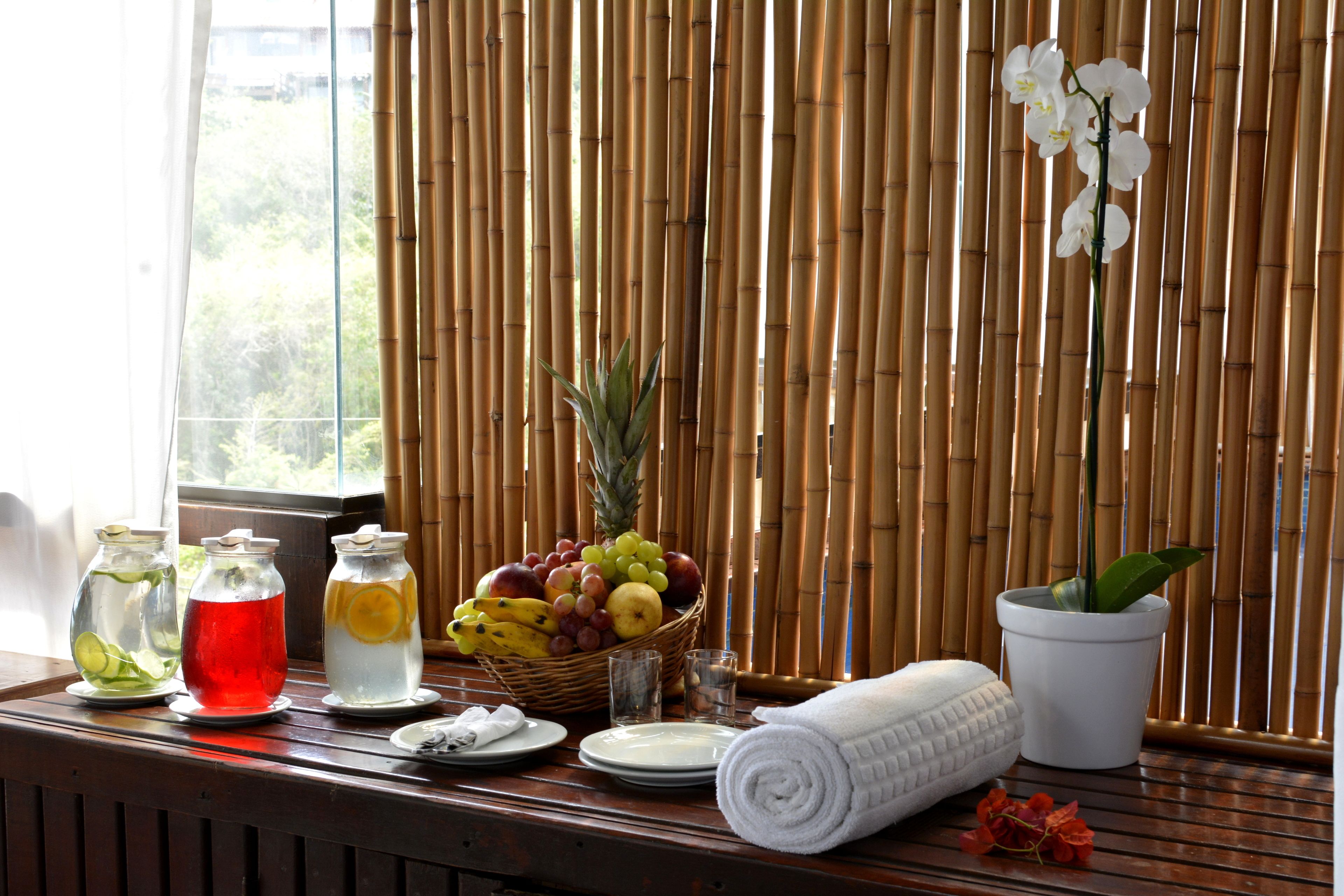 A table with a fruit basket, a potted plant, and a rolled towel.