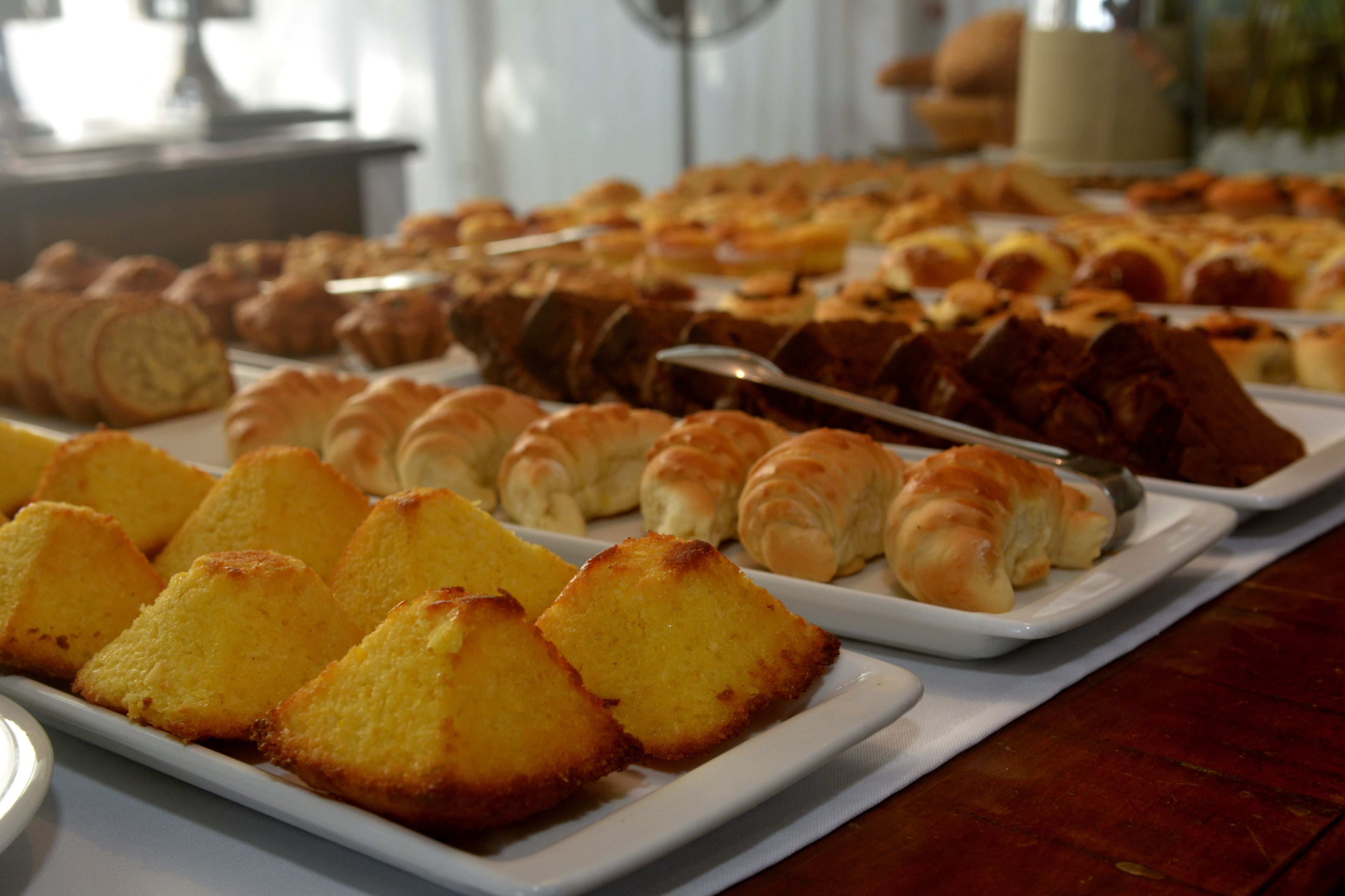 Une table de buffet proposant diverses viennoiseries, notamment du pain, des muffins et des pâtisseries.