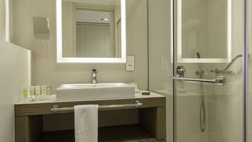 A modern bathroom with a glass-enclosed shower, a large mirror, and a vanity with a towel hanging.