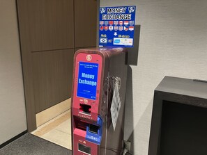 Un cajero de cambio de divisas con un cartel que muestra diversas monedas y opciones de tarjeta IC.