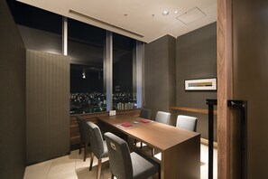 Un salón de conferencias con vista a la ciudad, amplias ventanas y una larga mesa con sillas.