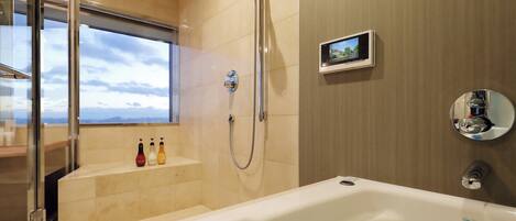 A modern bathroom with a bathtub, a glass shower enclosure, and a small digital screen on the wall.