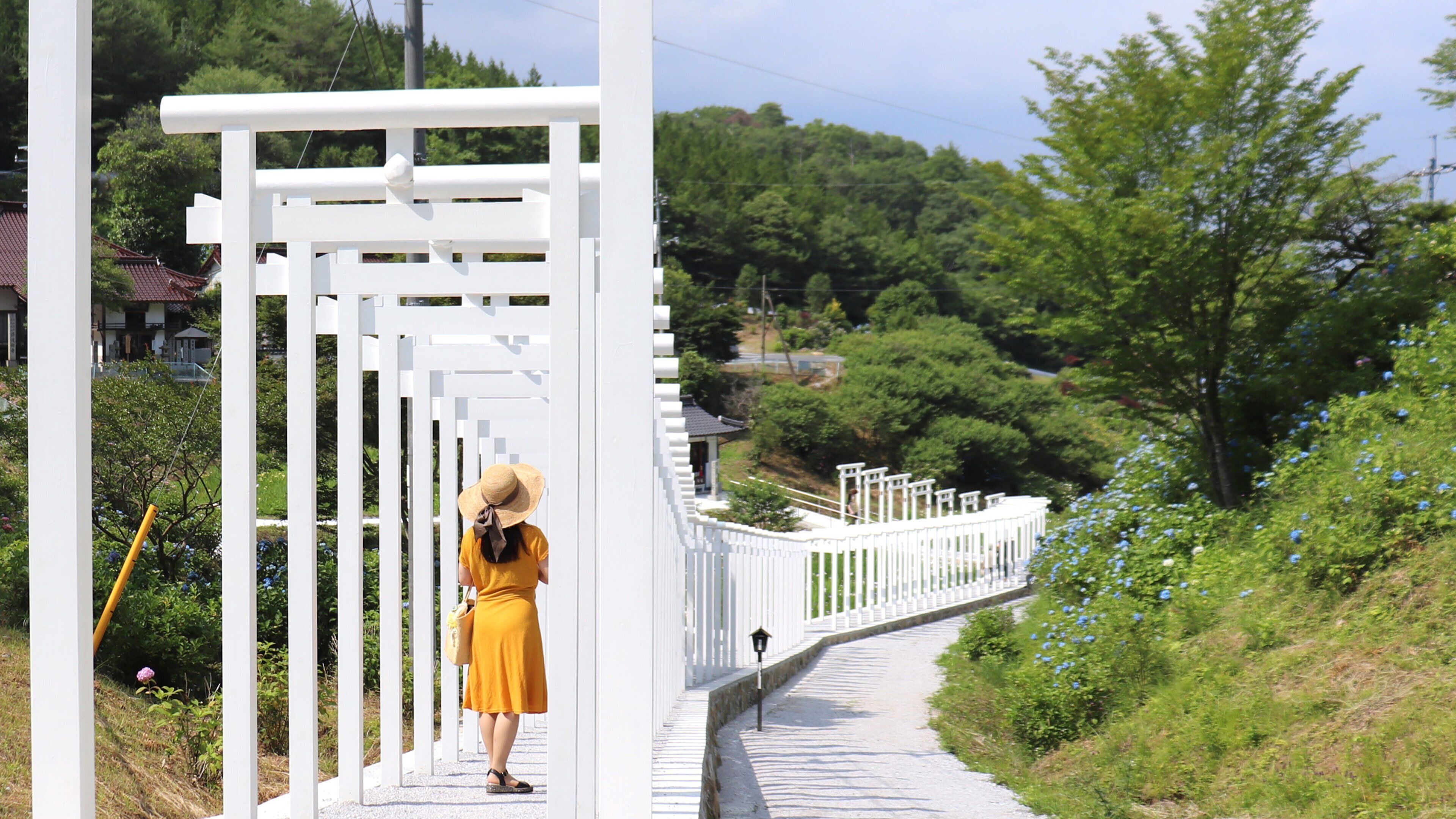 A pathway with white railings and a person walking.