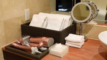 A bathroom with a wicker basket containing towels, a hairdryer, and other toiletries.
