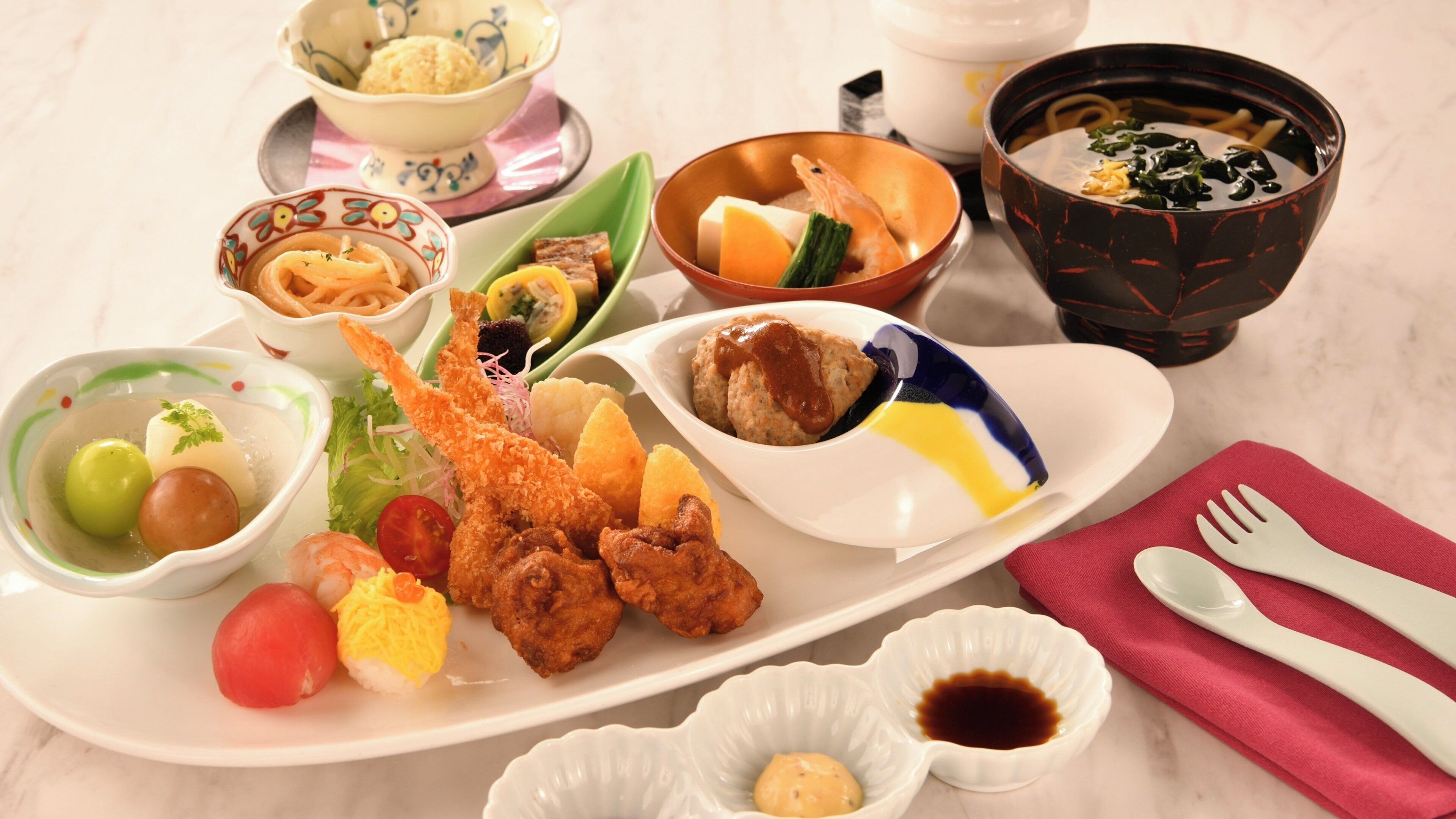 Variedade de pratos japoneses em uma bandeja, incluindo sushi, tempurá e outros aperitivos.