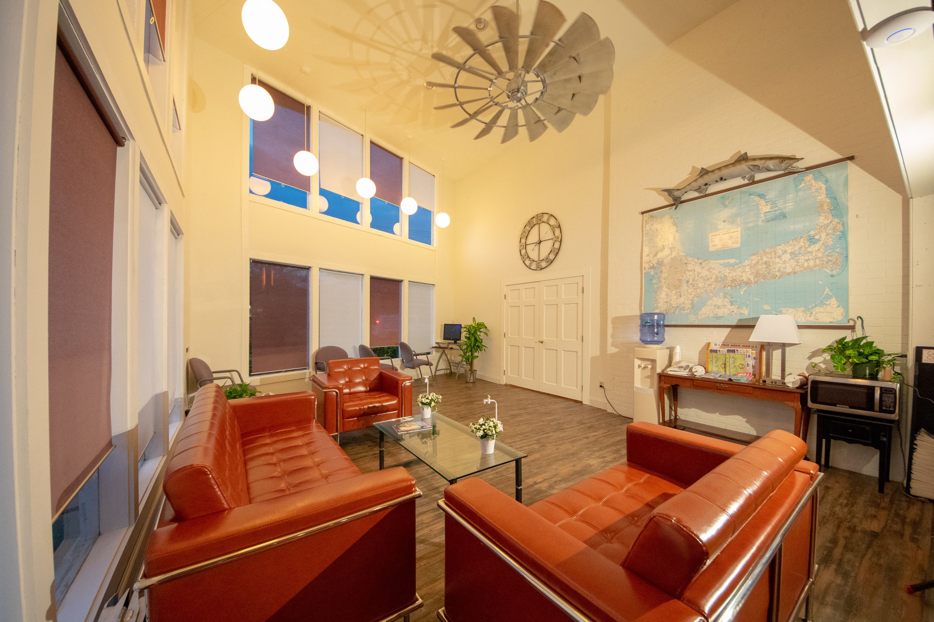 Ein geräumiges Wohnzimmer mit Ledersofas, einem Glastisch, einer Decke im Windmühlendesign, einer Karte an der Wand und einem Fernseher.