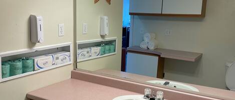 Un baño con encimera rosa, lavabo blanco, espejo y dos adornos de estrella de mar.