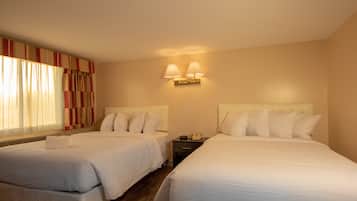 Une chambre d’hôtel avec deux lits, une table de chevet, une lampe et une fenêtre avec des rideaux.