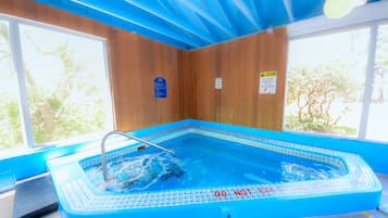 An indoor swimming pool with a blue interior, surrounded by wooden walls and large windows.
