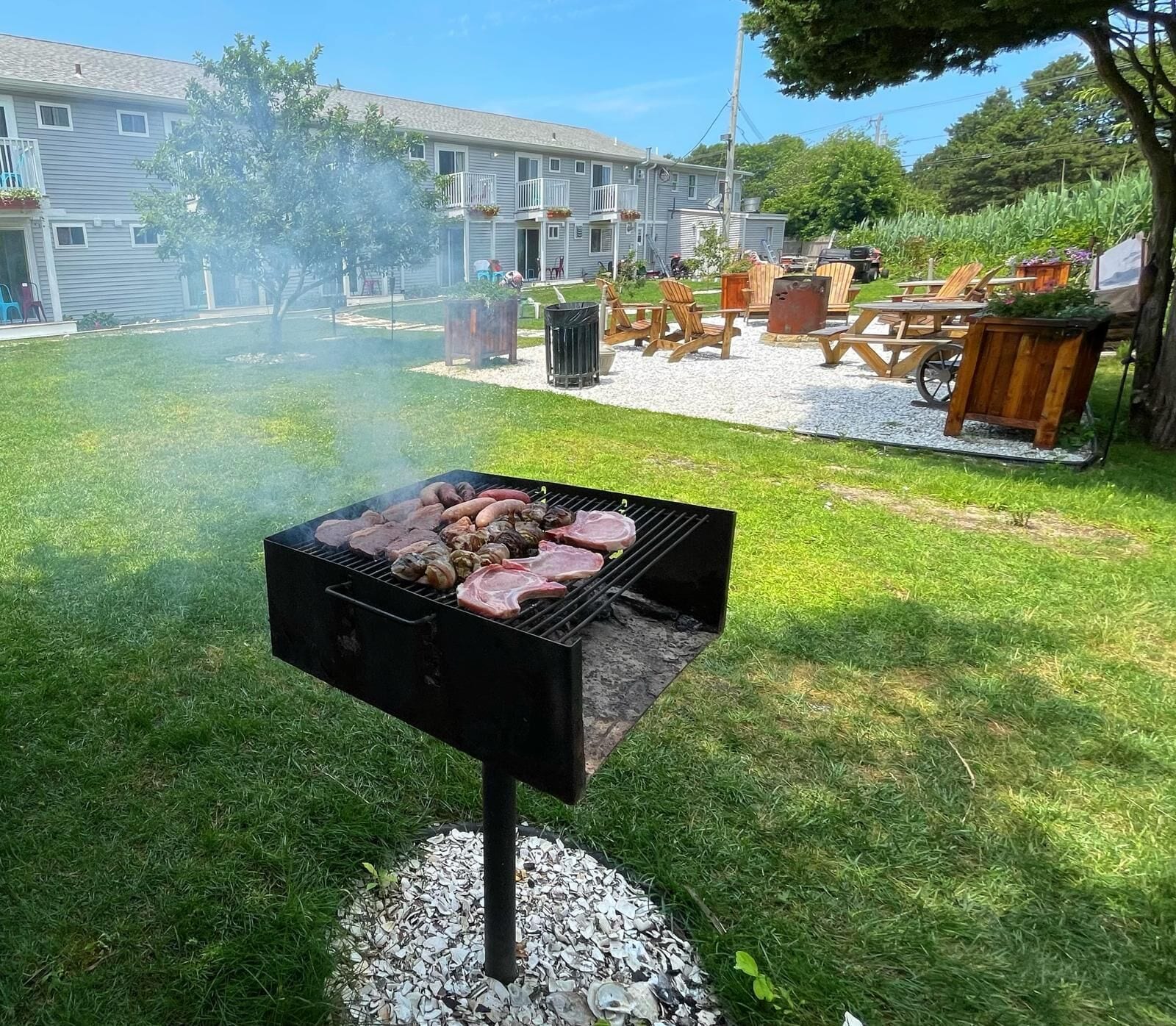A backyard with a grill, outdoor furniture, and a building in the background.