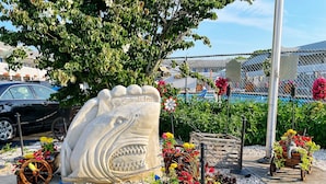 A decorative shark sculpture with the text "Cape Sands Inn" at a beachside location.