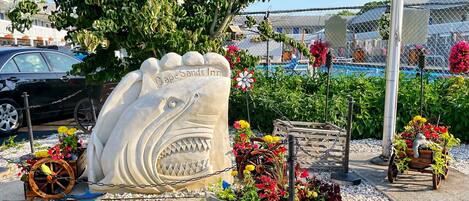 A decorative shark sculpture with the text "Cape Sands Inn" at a beachside location.