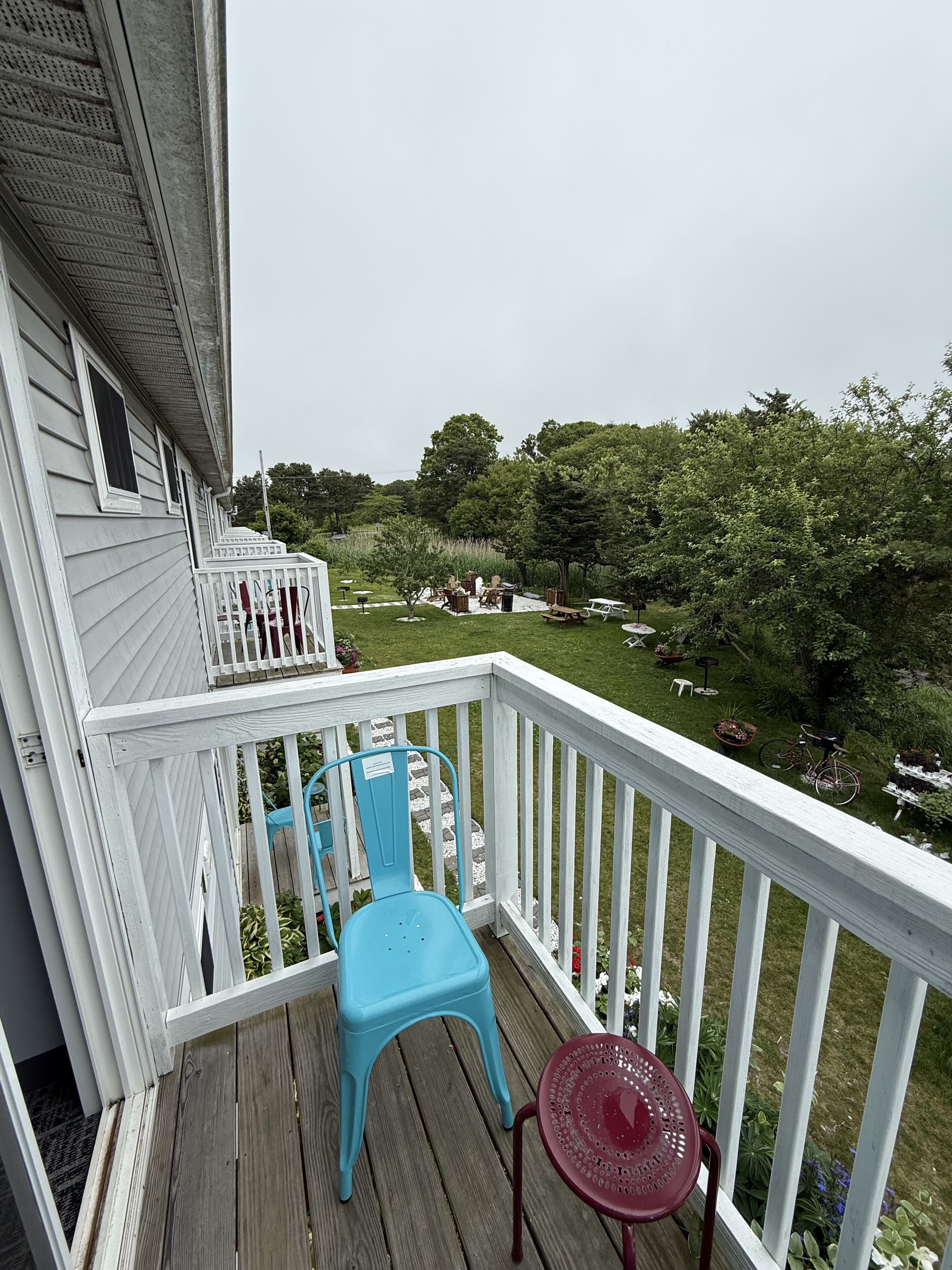 A wooden deck with a white railing, a blue chair, and a small table.