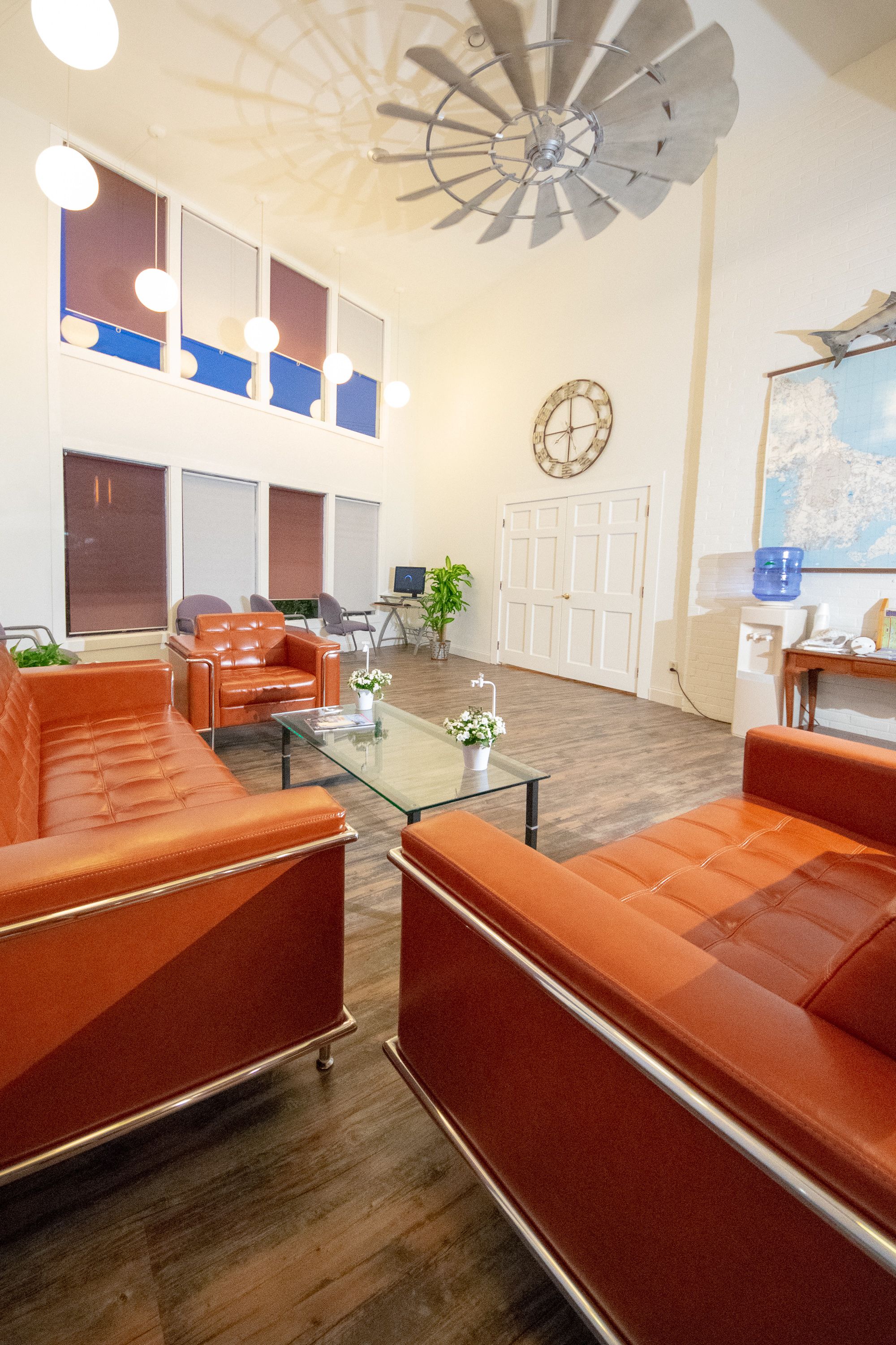A spacious living area with leather sofas, a glass coffee table, and a ceiling fan.